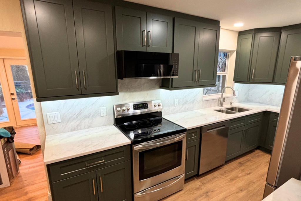 Charcoal shaker cabinets with white marble-look countertops, full-height backsplash, stainless range, and dishwasher